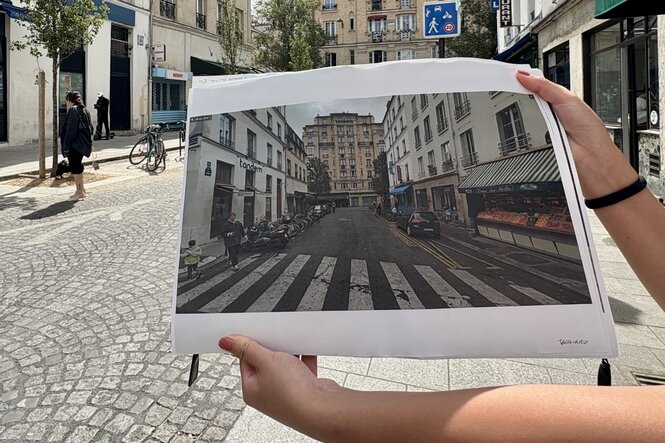 Hände halten ein Bild eines Zebrastreifens vor einer Straße
