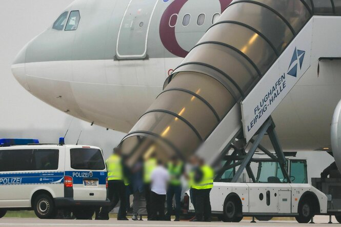 Gangway eines Flugzeugs, umstellt von Männern in Warnwesten, Menschen besteigen das Flugzeug