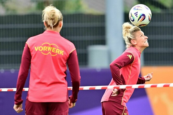 Zwei deutsche Spielerinnen stehen auf dem Trainingsplatz und Linda Dahlmann übt Kopfball