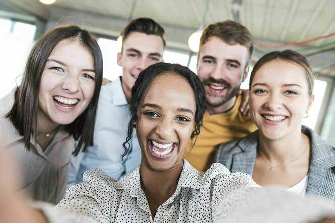 Fünf junge Menschen, sind bester Laune und lachen, machen ein Selfie