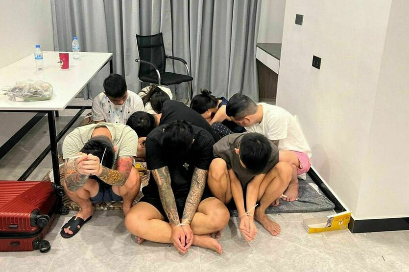 Festgenommene Mitarbeiter eines Betrugszentrums in Phnom Penh verbergen ihre Gesichter, als sie am 16. Juli von der Polizei präsentiert werden
