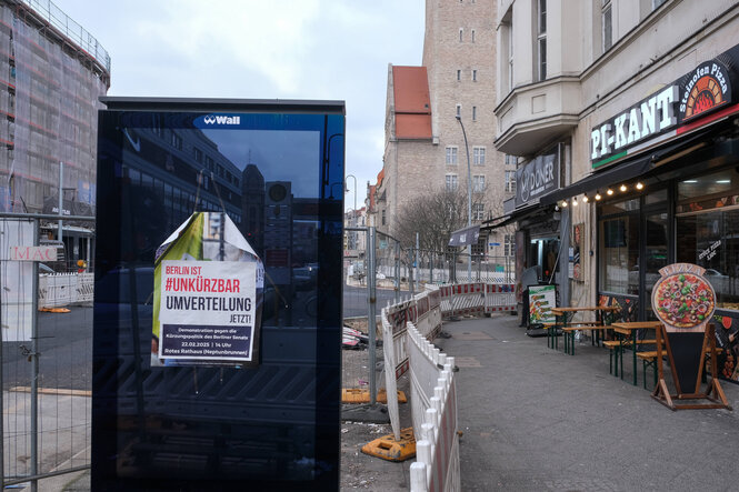 Ausgeschaltete Werbetafel mit Plakat, auf dem "Unkürzbar Berlin" steht
