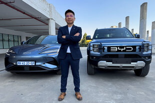 Der General-Manager von BYD posiert vor zwei BYD Modellen