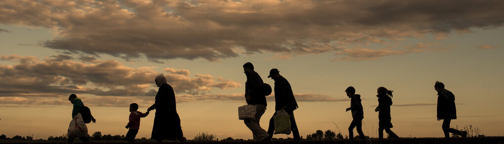 Silhouetten von Menschen die durch eine abendliche Landschaft laufen
