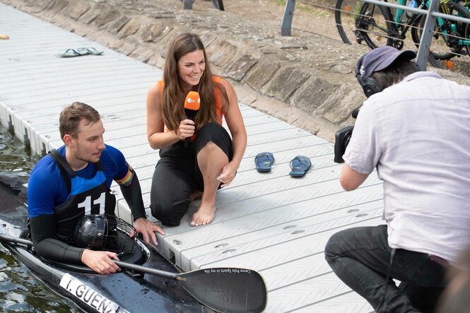 Sportreporterin Stiefvatter interviewt einen kanuten, der in seinem Boot sitzt