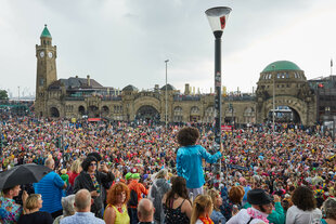 Menschen in bunter Verkleidung stehen an den Landungsbrücken beim Schlagermove in Hamburg 2019