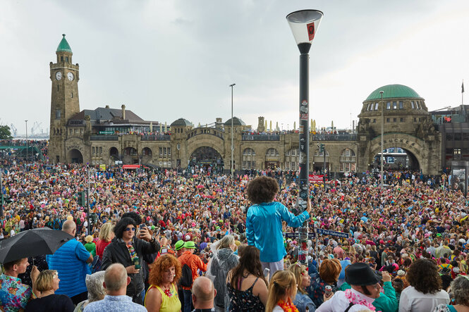 Menschen in bunter Verkleidung stehen an den Landungsbrücken beim Schlagermove in Hamburg 2019