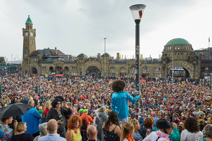 Menschen in bunter Verkleidung stehen an den Landungsbrücken beim Schlagermove in Hamburg 2019