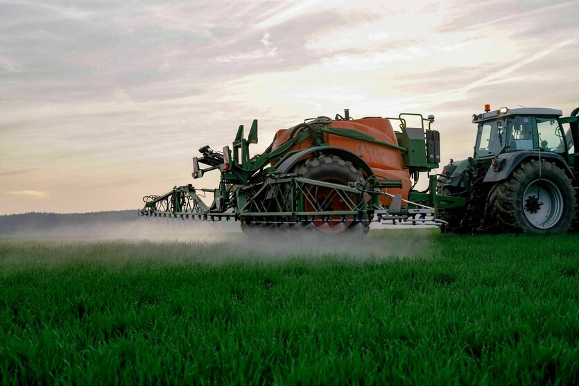 Landwirt spritzt gegen Abend sein Getreide gegen Unkraut, Sprühnebel im Gegenlicht