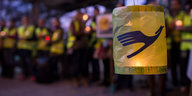 Eine Laterne mit dem Symbol der Lufthansa, im Hintergrund Menschen