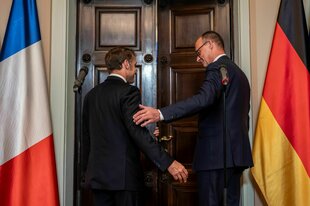 Emmanuel Macron und Friedrich Merz stehen vor einer Tür