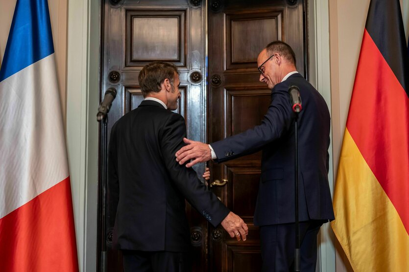 Emmanuel Macron und Friedrich Merz stehen vor einer Tür