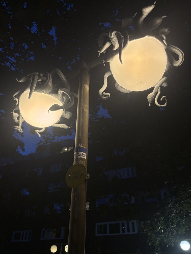 Eine Straßenlaterne, auf der eine Plastik in der Form mehrerer Schlangen platziert