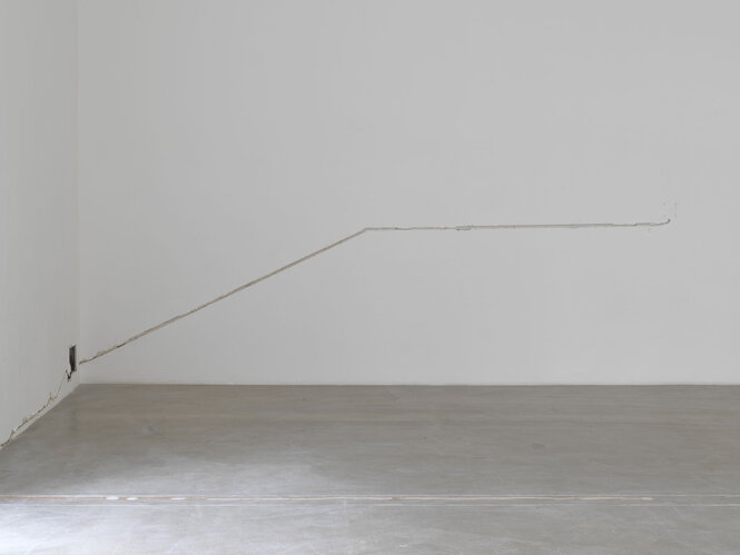Blick in die karge Ausstellung von Ghislaine Leung, ein Kabel an der Wand ist freigelegt