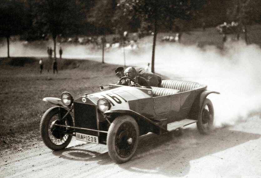 Autorennen 1924 - schwarz-weiß Foto, zwei Männer in einem offenen Auto ziehen eine Staubwolke hinter sich her