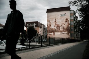 Straßenszen in Spremberg, auf ein Wohnhaus ist ein historische Stadtansicht gemalt