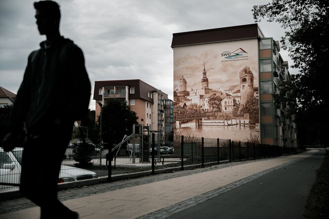 Straßenszen in Spremberg, auf ein Wohnhaus ist ein historische Stadtansicht gemalt