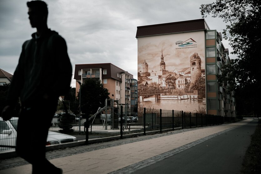 Straßenszen in Spremberg, auf ein Wohnhaus ist ein historische Stadtansicht gemalt