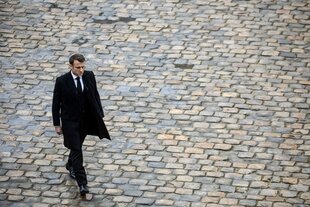 Der französische Präsident läuft nachdenklich über Kopfsteinpflaster