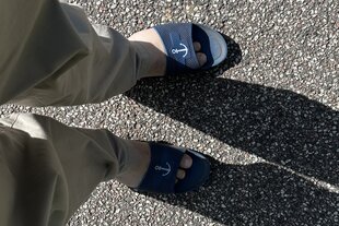 Zwei Füße in blauen Badelatschen mit Anker-Motiv.