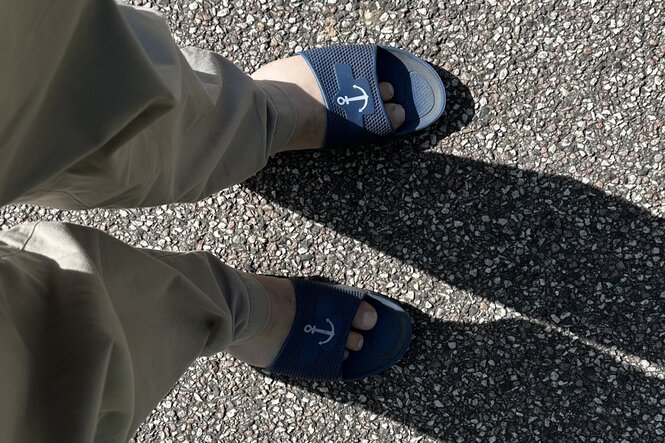 Zwei Füße in blauen Badelatschen mit Anker-Motiv.