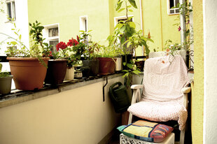 Auf einem Balkon steht ein gartenstuhl und viele Pflanzen