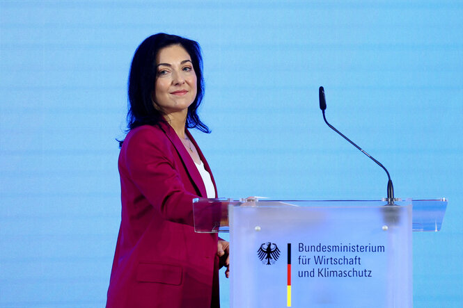 Katherina Reiche steht seitlich vor einem Rednerpult im Wirtschaftsministerium