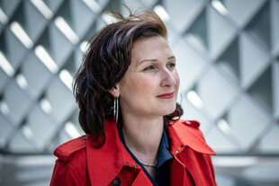 Porträt von Ferda Ataman - sie trägt eine rote Jacke und roten Lippenstift