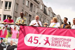 Kai Wegner auf einem Bus vor einem pinken Banner