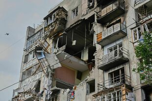 Ein von Bomben getroffenes Mehrfamilienhaus in Odessa, in der Wand klafft ein rießiges Loch, die Holzverkleidung der Balkone hängt in der Luft