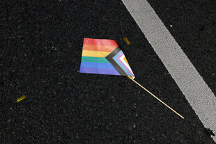 Eine Regenbogenfahne aus Papier liegt zertreten am Boden am Tag des CSDs im Jahr 2024