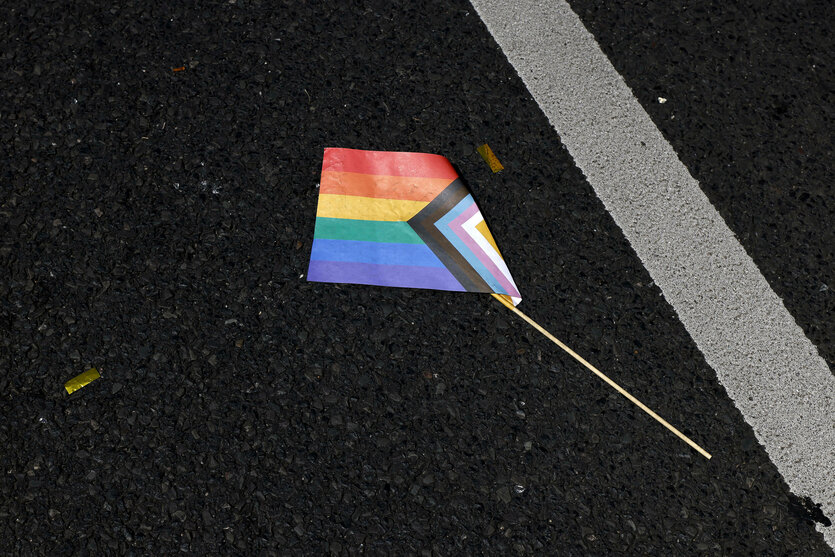 Eine Regenbogenfahne aus Papier liegt zertreten am Boden am Tag des CSDs im Jahr 2024