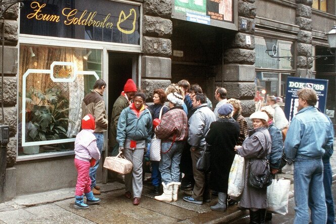 Schlange vor einer Hähnchenbraterei mit dem Namen "Zum Goldbroiler"