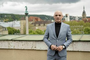 Ein Mann im Anzug steht vor einer Stadtkulisse
