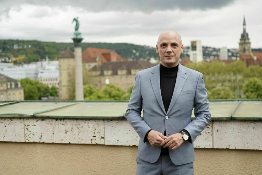 Ein Mann im Anzug steht vor einer Stadtkulisse