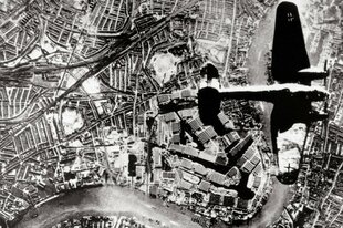 Eine Luftaufnahme zeigt wie ein Flugzeug über eine Stadt fliegt