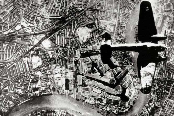 Eine Luftaufnahme zeigt wie ein Flugzeug über eine Stadt fliegt