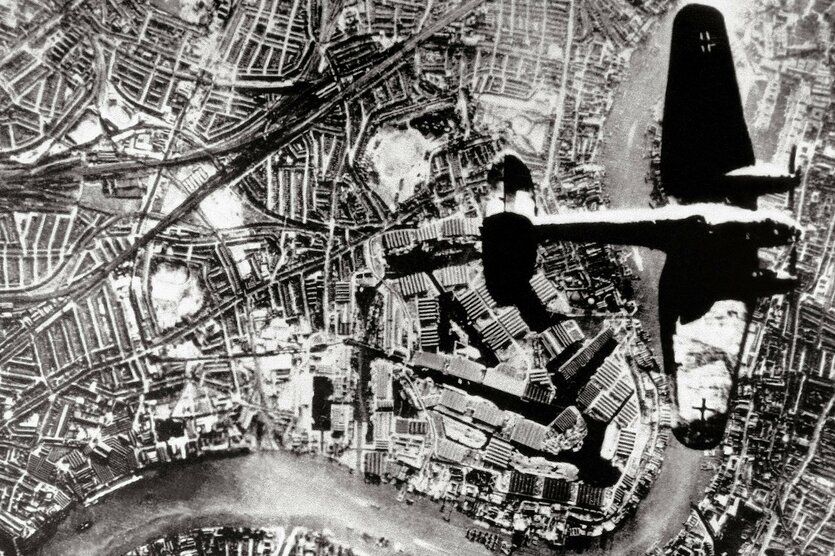 Eine Luftaufnahme zeigt wie ein Flugzeug über eine Stadt fliegt
