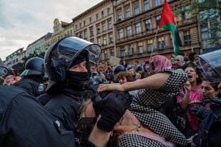 Eine Frau wird auf der Internationalist Queer Pride von Polizisten mit einem Schmerzgriff verhaftet