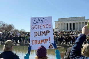 Bei einer Demonstration hält jemand ein Schild hoch, auf dem steht: save science dump trump