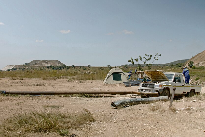Ein AVZ-Mitarbeiter pumpt Diesel in einen Generator, der Wasser aus dem altern "Roche Dure" Tagebau ableitet. Die Berge im Hintergrund sind 'Tailings Dumps' aus früheren Bergbauaktivitäten. Tantalex hofft, die Tailings Dumps in naher Zukunft zur Gewinnung von Lithium abbauen zu können.