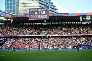Stadiontribünde mit Anzeigetafel, die Zuschauerrekord vermeldet