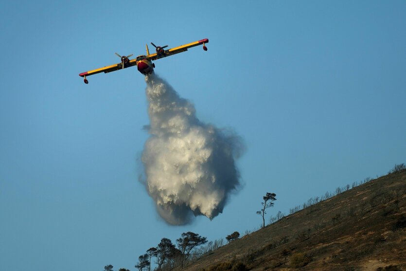 Ein Löschflugzeug versprüht Wasser auf einem Hügel in Thymari, südlich von Athen