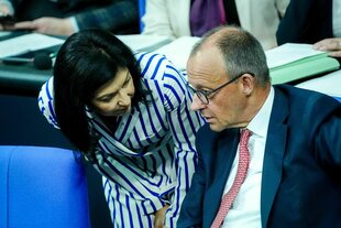 Katherina Reiche beugt sich zu Kanzler Merz runter