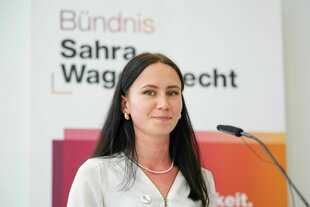 Eine Frau hinter einem Mikrofon schaut freundlich in die Kamera