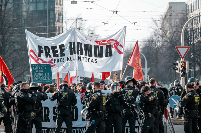 Demonstrierende halten ein Banner in die Höhe, auf dem steht: