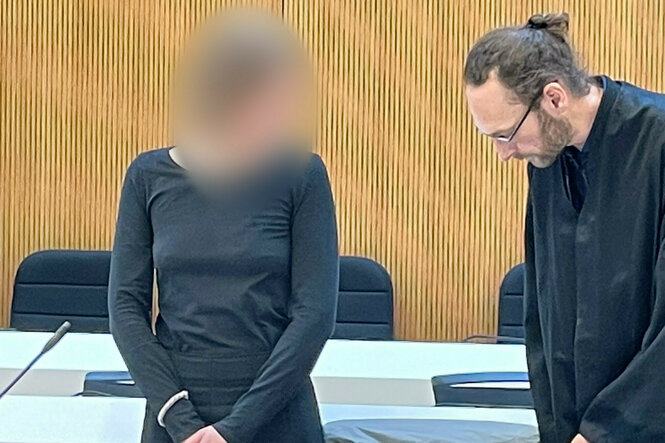 Eine Peron und ein Anwalt stehen in einem Gerichtssaal