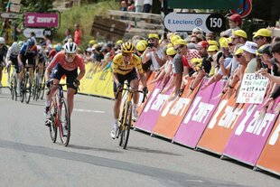 Zwei Frauen auf Rennrädern sprinten um die Wette, am Rand jubeln die Fans