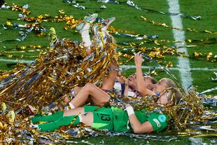 Englische Spielerinnen liegen nach dem Schlusspiff auf dem Rasen und strampeln sich mit den Beinen durch Lamettafäden