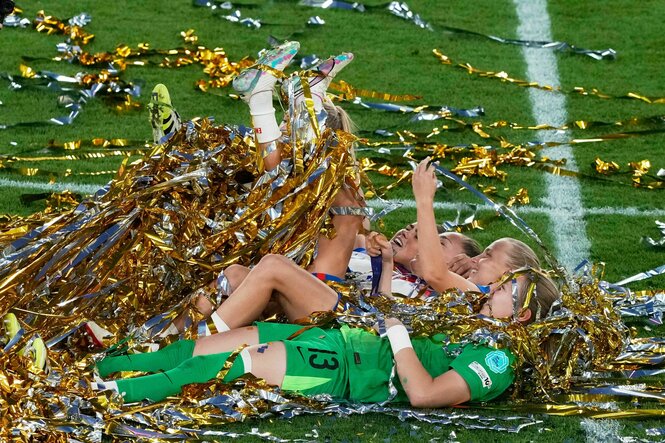Englische Spielerinnen liegen nach dem Schlusspiff auf dem Rasen und strampeln sich mit den Beinen durch Lamettafäden